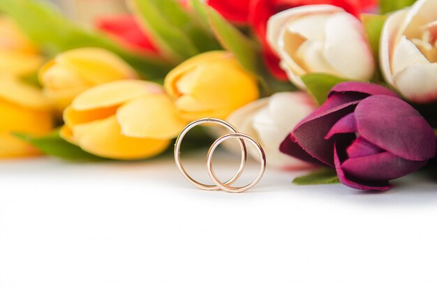 Anillos de boda y flores aisladas sobre fondo blanco