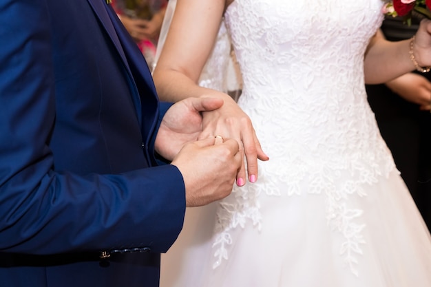 Anillos de boda y manos de novios. jóvenes novios en la ceremonia.