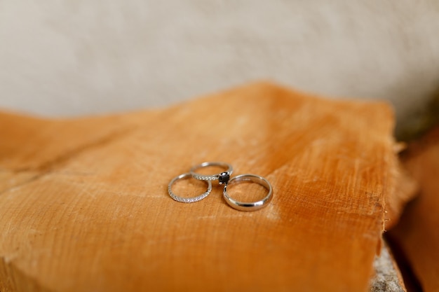 Anillos de boda de oro y anillo de compromiso sobre fondo borroso de textura de madera lisa