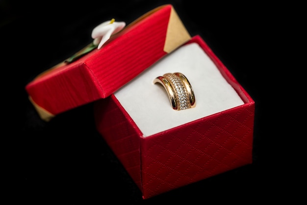 Anillos de boda de oro en caja roja actual sobre fondo negro