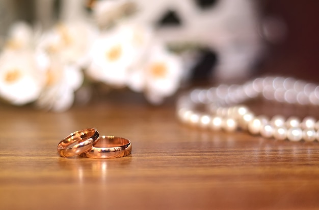 Anillos de boda de oro junto al ramo de la novia en una mesa de madera