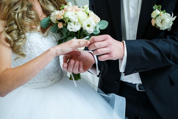 Anillos de boda de oro en manos de los recién casados el día de la boda