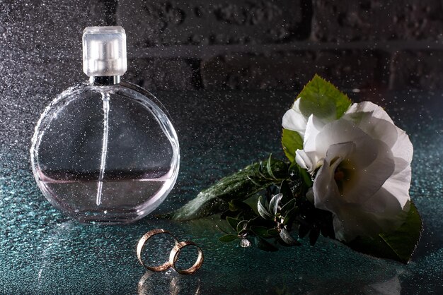 Foto anillos de boda de perfume en un fondo oscuro mañana de la novia antes de la ceremonia