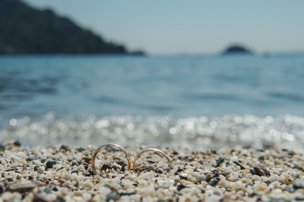 Anillos de boda en la playa en el mar azul de fondo