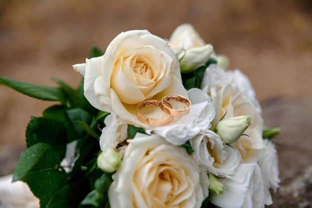 Anillos de boda y ramo en el fondo