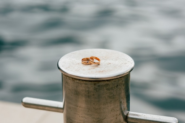 Anillos de boda de los recién casados cerca del mar anillos de compromiso de oro