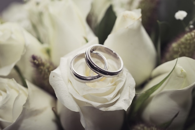 Foto anillos de boda en rosa blanca ramo