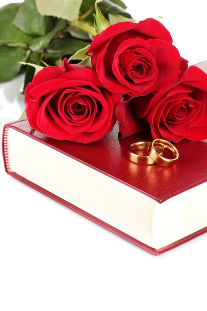 Anillos de boda con rosas en la Biblia aislado en blanco