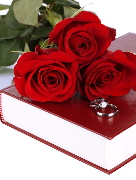 Anillos de boda con rosas en la Biblia aislado en blanco