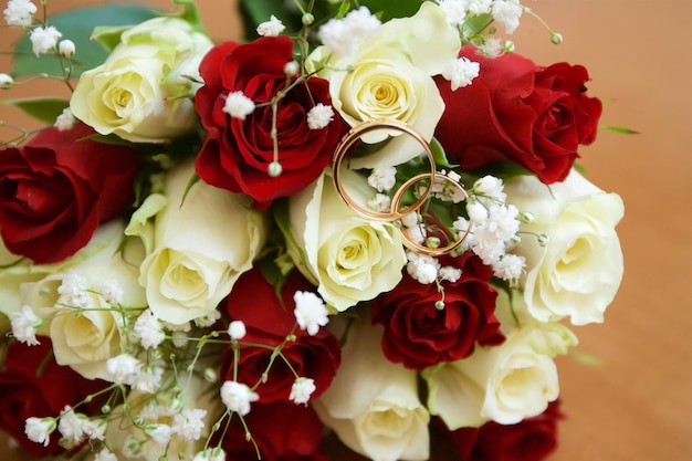 Los anillos de boda yacen en flores de rosa en un ramo