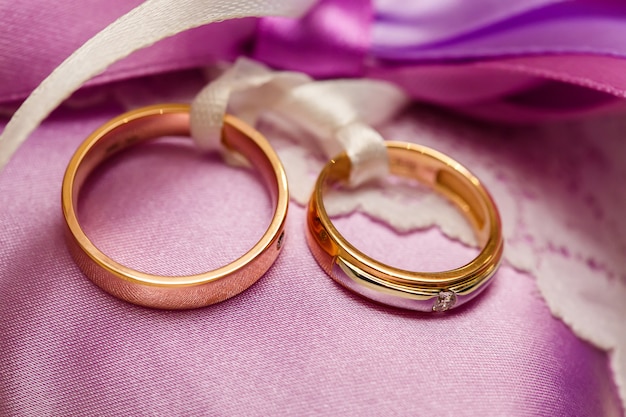 Anillos de bodas de oro en la almohada de encaje morado. Concepto de matrimonio