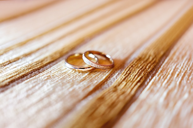 Anillos de bodas de oro con los diamantes en fondo beige de la tela.