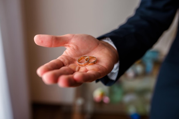 Anillos de bodas de oro en la palma del novio el día de la boda