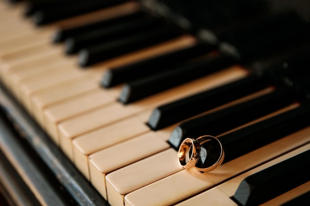 Anillos de bodas de oro en primer plano de las teclas del piano