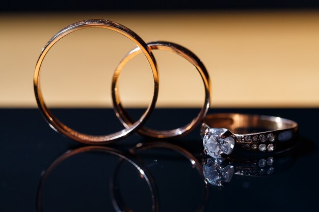 Anillos de bodas de oro para los recién casados el día de la boda sobre un fondo negro con gotas de agua. Joyas