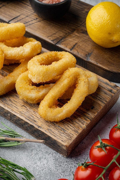 Anillos de calamares empanizados horneados al horno, en placa para servir, sobre fondo de tabla de piedra gris