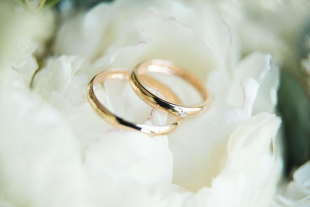 Anillos de compromiso de boda y fondo de ramo de boda de flores, enfoque selectivo, macro