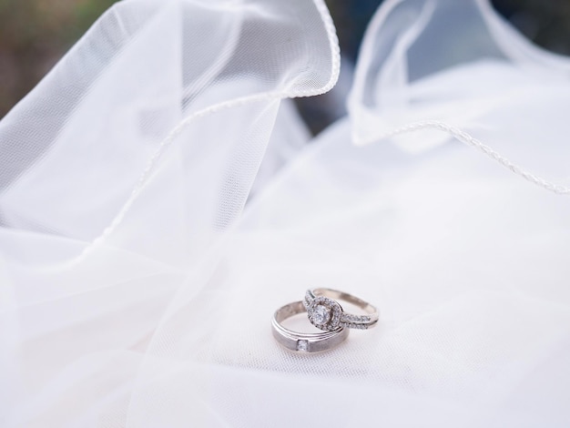 Anillos de compromiso de diamantes en el velo nupcial Accesorios de boda Día de San Valentín y concepto de día de bodas.