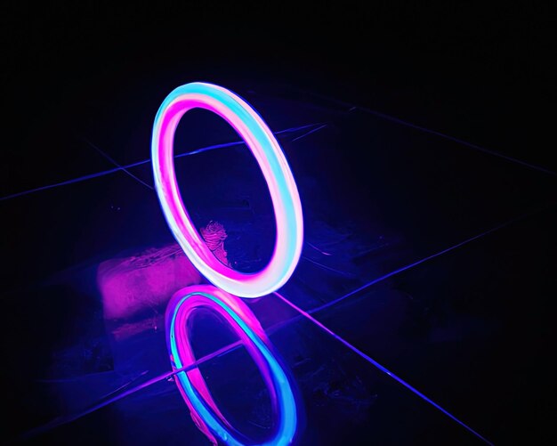 Anillos de luz rosa y azul magenta y turquesa con reflejos en el suelo fondo negro anillos de luz en movimiento