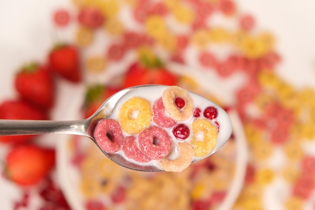 Anillos de maíz con arándanos rojos en leche en una cuchara