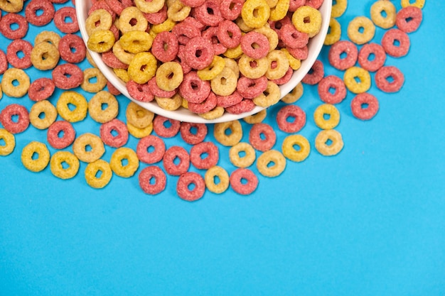 Anillos de maíz de polvo de desayuno rápido en un plato sobre un fondo azul.