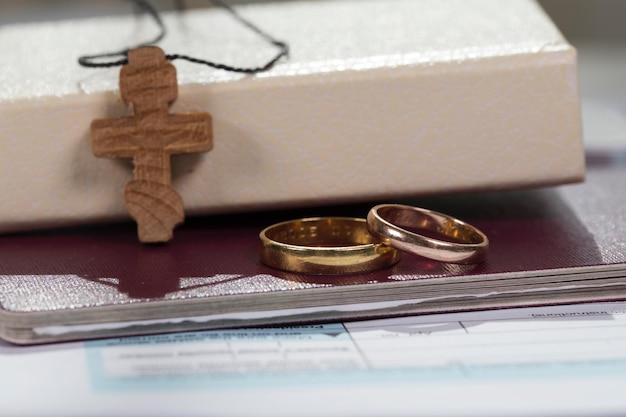 Anillos de matrimonio cerca de la biblia con cruz de madera. De cerca