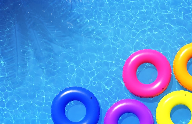 Anillos de natación coloridos en piscina azul, ilustración 3d