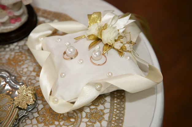 Los anillos de oro para la boda están en una almohada decorativa.