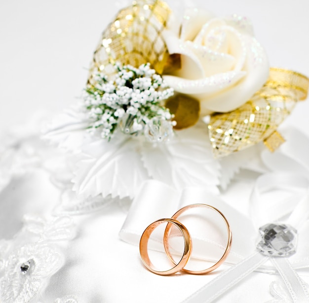 Anillos de oro de boda sobre una almohada blanca