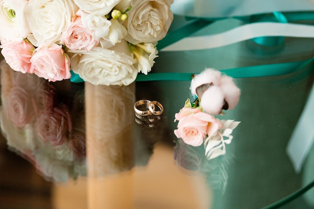 Anillos de oro y un hermoso ramo de rosas en el fondo detallan las tradiciones de la boda