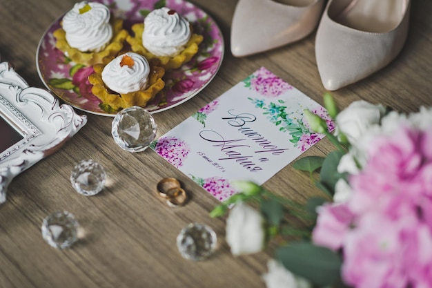 Anillos de oro de los recién casados en la mesa entre los zapatos de flores y