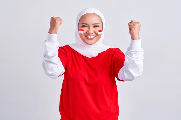 Animada jovem muçulmana asiática em camiseta branca vermelha comemorando o dia da independência indonésia em 17 de agosto isolada em fundo branco