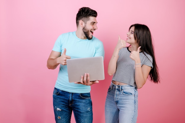 Animado feliz sorridente jovem casal homem e mulher, juntamente com o laptop