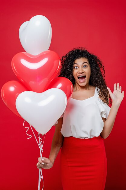 Animado gritando mulher negra com balões em forma de coração vermelhos e brancos isolados