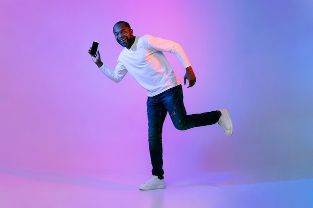 Animado homem afro-americano correndo com o telefone na mão
