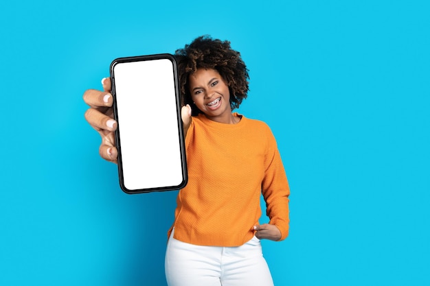 Animado jovem negra mostrando telefone celular com maquete