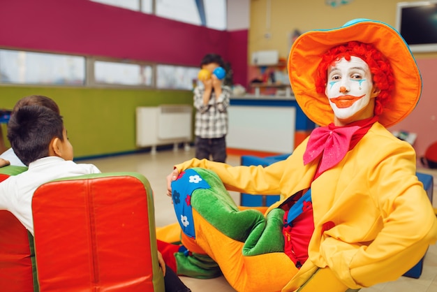 Animador de palhaço engraçado e grupo de meninos. Comemoração de aniversário na sala de jogos