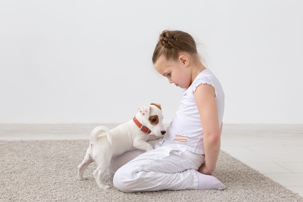 Animais de estimação e conceito de animal - menina criança brincando com o cachorrinho jack russell terrier