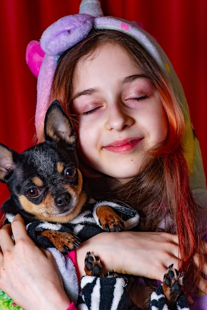 Animais de estimação e proprietários. menina e o cachorro dela sobre um fundo vermelho. Uma garota com um cachorro nos braços. Menina adolescente