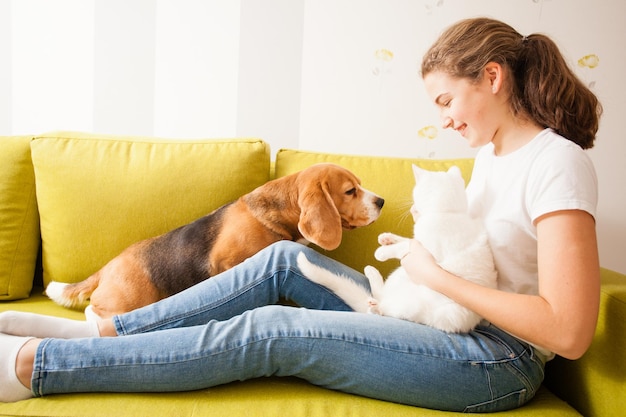 Animais e seu dono estão sentados no sofá verde