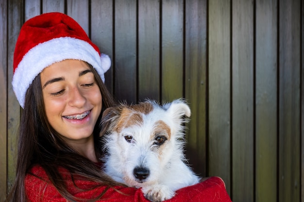 Animal de estimação amor no Natal com a garota. Momentos felizes, rosto sorridente com chapéu de Natal. Saudações e alegria.