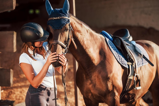 El animal está vestido de azul. Amazona en uniforme y casco protector negro con su caballo.