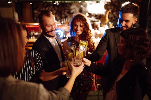 Animando y bebiendo cócteles Grupo de amigos de fiesta en una discoteca y brindando bebidas