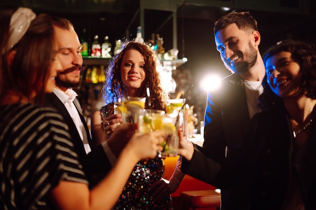 Foto animando y bebiendo cócteles grupo de amigos de fiesta en una discoteca y brindando bebidas