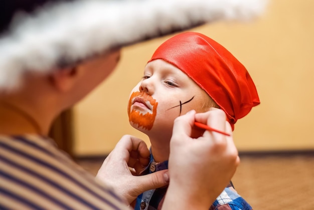 Animator macht Piratenmalerei auf dem Gesicht des Kleinkindes auf der Kindergeburtstagsfeier