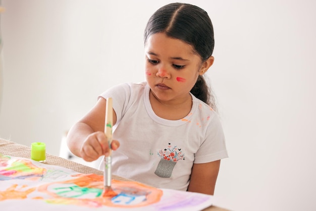 Anime a sus hijos a ser creativos Foto de una adorable niña pintando mientras está sentada en una mesa