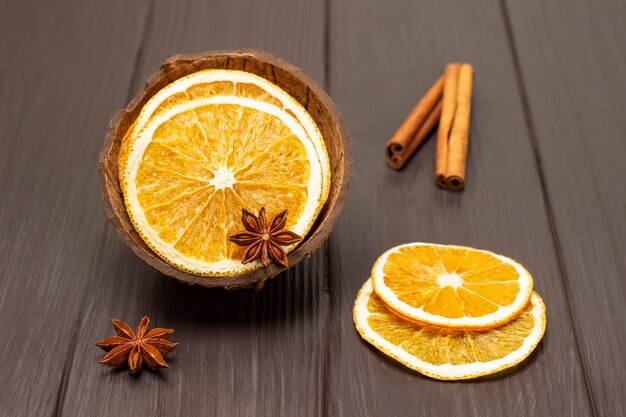 Anís estrellado y rodajas de naranja secas en cáscara de coco Palitos de canela sobre la mesa