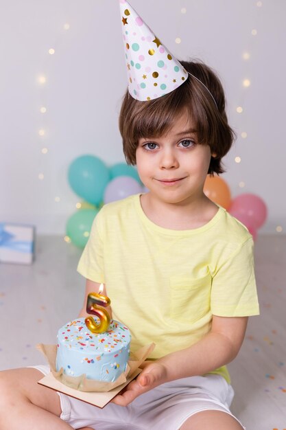 Aniversariante bonitinho no bolo de chapéu com vela cinco balões feliz aniversário