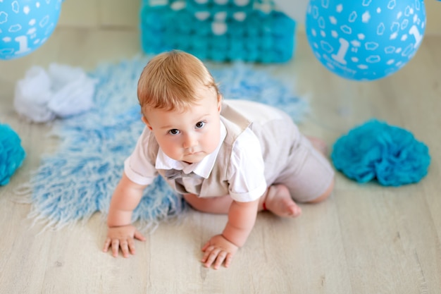 Aniversário criança menino de 1 ano de idade, vista superior, bebê rastejando entre balões de terno e gravata borboleta