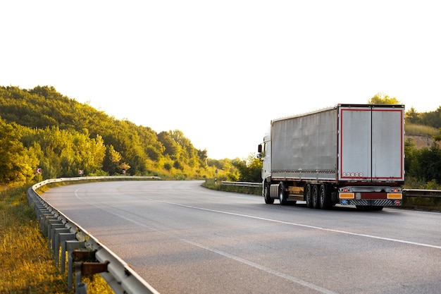 Ankommender LKW auf der Straße in einer ländlichen Landschaft bei Sonnenuntergang